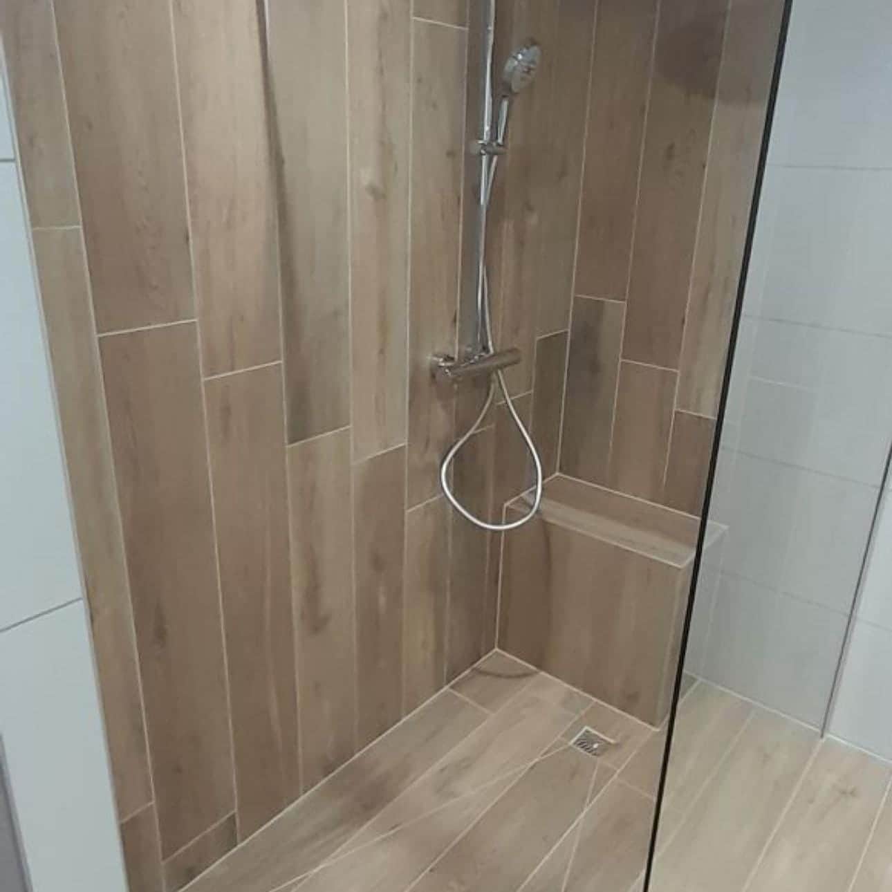 Douche carrelée imitation bois posée en décalé, banc maçonné et colonne thermostatique chromée