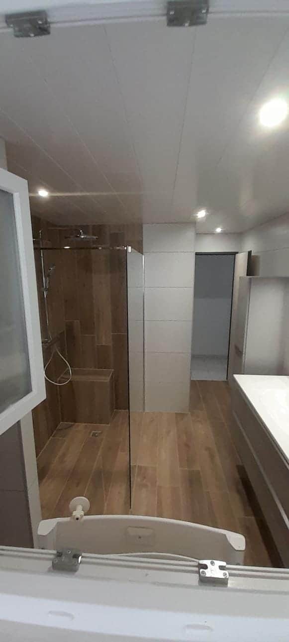 Douche à l'italienne en carrelage imitation bois avec banc maçonné et paroi vitrée, par AML Plomberie