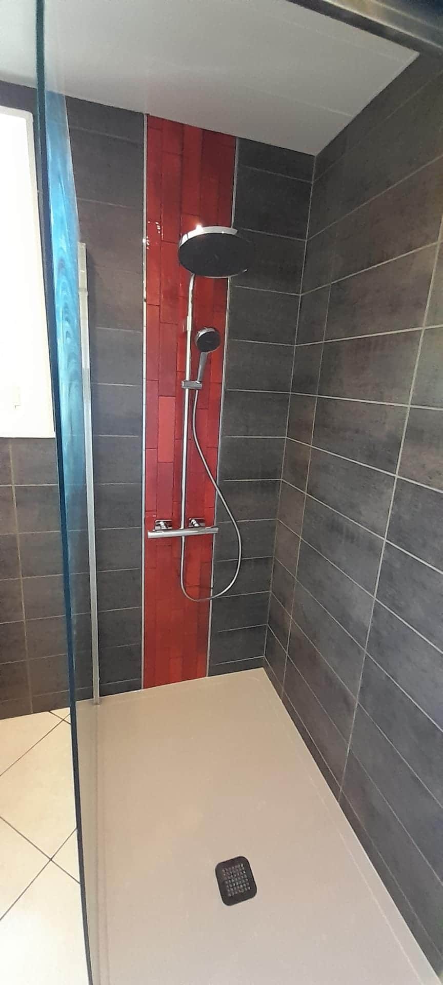 Douche avec receveur extra-plat, faïence anthracite, bande de carrelage rouge et colonne thermostatique