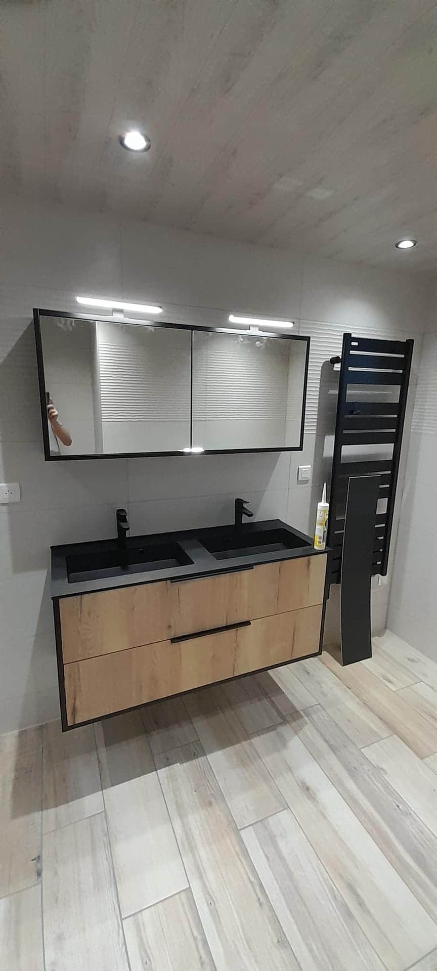 Double vasque noire sur meuble bois suspendu, miroir éclairé et sèche-serviettes noir, dans le Doubs