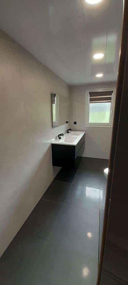 Salle de bain avec double vasque sur meuble noir suspendu, grand miroir et sol anthracite